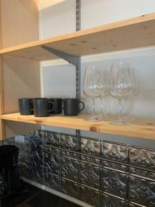 three wine glasses on a shelf in a kitchen at Den Street Cottage in Los Alamos