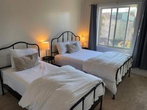 a bedroom with two beds and a window at Den Street Cottage in Los Alamos