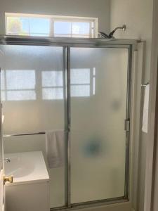 La salle de bains est pourvue d'une douche avec une porte en verre. dans l'établissement Den Street Cottage, à Los Alamos