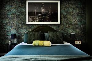a bedroom with a blue bed with a picture on the wall at Boatshed Villa Green Door in Daylesford