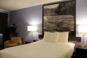 a hotel room with a bed and a painting on the wall at Super 8 by Wyndham Kamloops On The Hill in Kamloops