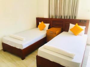 2 bedden in een kleine kamer met gele kussens bij Marian Villa in Katunayaka