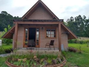 a tiny house with a porch and chairs in a yard at Refúgio Verde - Cabana Quero-Quero in Nova Petrópolis