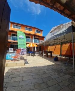 patio z krzesłami i parasolami przed budynkiem w obiekcie Pousada paraiso das conchas hostel w mieście Cabo Frio