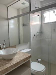 a bathroom with a sink and a toilet and a glass shower at Muito confortável, vista do mar, todo climatizado in Bombinhas