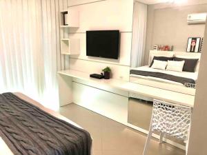 Schlafzimmer mit einem Schreibtisch, einem TV und einem Bett in der Unterkunft Muito confortável, vista do mar, todo climatizado in Bombinhas