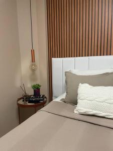 a bedroom with a white bed with a wooden headboard at Muito confortável, vista do mar, todo climatizado in Bombinhas