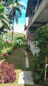 a path next to a house with a palm tree at Chalé no morro in Ubatuba