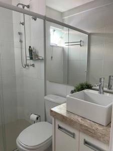 La salle de bains blanche est pourvue d'un lavabo et de toilettes. dans l'établissement Muito confortável, vista do mar, todo climatizado, à Bombinhas