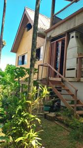 uma casa com uma escada de madeira que leva à porta da frente em Chalé no morro em Ubatuba