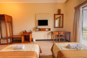 Habitación de hotel con 2 camas y TV en Hotel Griya Katarina, en Ambarawa