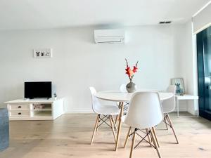 a white dining room with a white table and chairs at The Metropol 2BR Apt, In the heart of CBD 2b1b1c, Free parking, Wi-Fi in Canberra