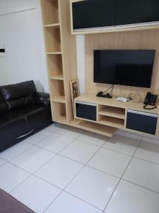 uma sala de estar com um sofá preto e uma televisão de ecrã plano em Lagoa Flat Service RM Hopsedagem em Caldas Novas