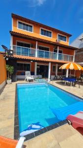 a swimming pool in front of a house at Pousada paraiso das conchas hostel in Cabo Frio