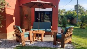 un patio con mesa, sillas y sombrilla en Hermosa casa con piscina climatizada entre el mar y las sierras en Bella Vista - Piriápolis en Bella Vista