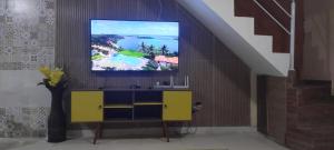 a living room with a tv on a wall at Casa com Piscina em Ubatuba in Ubatuba