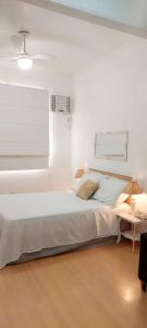 a white bedroom with a bed and a table at Bem Localizado Botafogo in Rio de Janeiro