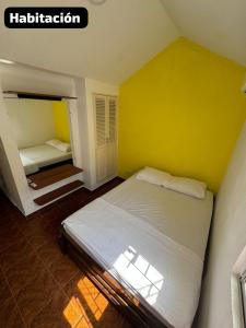 ein Schlafzimmer mit einem Bett und einer gelben Wand in der Unterkunft Encanto en Cartagena, aparatamento Duplex con vista al mar in Cartagena de Indias