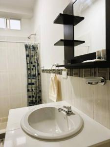 uma casa de banho branca com um lavatório e um chuveiro em Hermoso apartamento por estrenar em Puerto Baquerizo Moreno