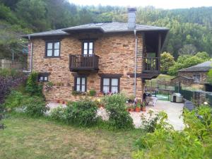 a brick house with a balcony in a yard at Hospedaje - Ferrería Quintá in Quiroga