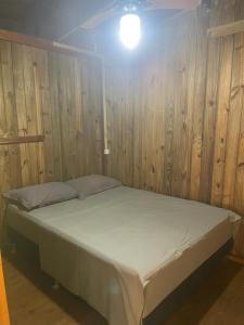 uma cama num quarto com uma parede de madeira em Pousada - Quintal do Rosa na Praia do Rosa
