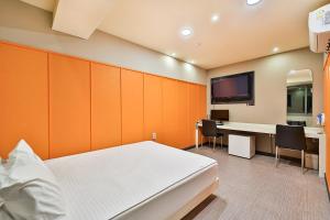 Dormitorio con cama, escritorio y TV en Top Motel Busan en Busan