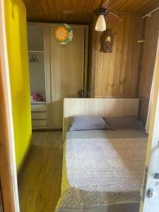 um quarto com uma cama e uma parede amarela em Pousada - Quintal do Rosa na Praia do Rosa