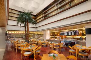 BinhaiにあるCrowne Plaza Tianjin Binhai Center, an IHG Hotelの木のテーブルと椅子、ヤシの木があるレストラン