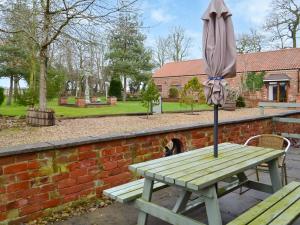 an umbrella sitting on a picnic table next to a brick wall at Daisy Cottage - Uk46262 in Tetney