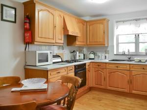 a kitchen with wooden cabinets and a wooden table at Daisy Cottage - Uk46262 in Tetney