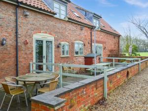 a brick building with a deck with tables and chairs at Daisy Cottage - Uk46262 in Tetney