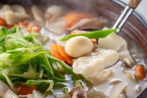 un tazón de sopa de fideos de pollo con zanahorias y verduras en KAMENOI HOTEL Aso, en Aso