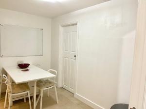 a white dining room with a white table and chairs at Two bedroom flat with a sofa bed living room in London