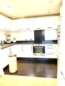 a kitchen with white cabinets and a stainless steel oven at Two bedroom flat with a sofa bed living room in London