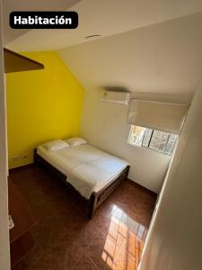 a small bedroom with a bed with a yellow wall at Encanto en Cartagena, aparatamento Duplex con vista al mar in Cartagena de Indias