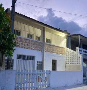 een wit huis met een wit hek ervoor bij Casa Próxima ao Mar em Tamandaré - Seu refúgio a 20 m da praia in Tamandaré