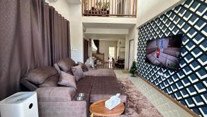 a living room with a couch and a tv on a wall at Amphawan in Ban Nong Khrai Luang