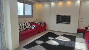 un soggiorno con 2 divani rossi e una TV di Comfy Luxurious Apartment in Central Location in Mansheyet El Bakry East Cairo a Il Cairo
