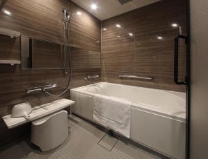 a bathroom with a tub and a toilet and a sink at Spa World HOTEL&RESORT in Osaka