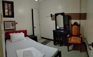 a bedroom with a bed and a chair and a mirror at V.F. Riton Apartelle in Laoag