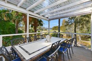 a white pergola on a deck with a table and chairs at Palm Cove Retreat in Umina