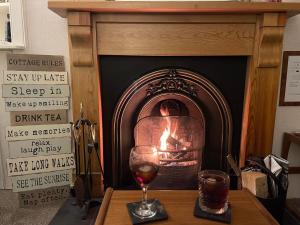 a glass of wine on a table in front of a fireplace at Moulin Cottage in Moulin