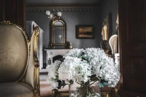 a vase of white flowers on a table next to a chair at Bishops Palace Ballarat in Wendouree