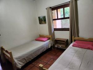 due letti in una stanza con finestra di Chalé Chácara Caminho do Vale CASA DE TEMPORADA a Nova Friburgo