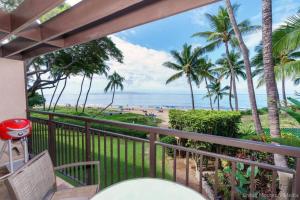 a balcony with a view of the beach and palm trees at Spacious Beachfront — Sleeps 6 — Ocean Views in Kihei