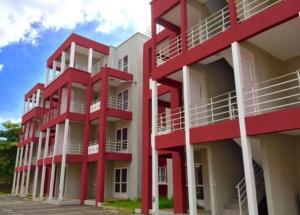 - un bâtiment rouge avec des balcons blancs à côté d'un parking dans l'établissement Red Lory residences apartment G1, à Pereybere