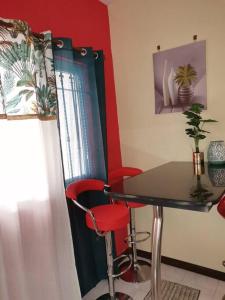 a dining room with a table and two red chairs at Red Lory residences apartment G1 in Pereybere +3 photos