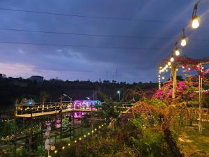 un puente con luces en un jardín por la noche en Khu Du lịch Nông trại Hải Đăng trên núi, en Gia Nghĩa