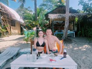a man and a woman sitting at a table on the beach at 8 Star Paradise in Locaroc