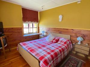a bedroom with a bed with a red and white blanket at Casa acogedora en hermoso entorno Chiloe in Rauco